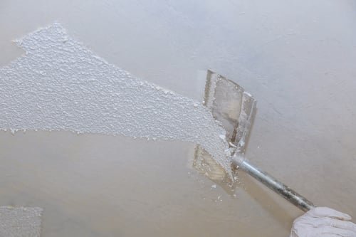 Ceiling being skim-coated with joint compound using a wide taping knife