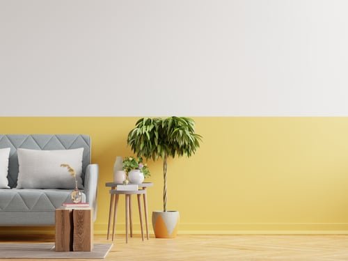 Living room with a soft yellow accent wall and grey sofa after an interior repaint